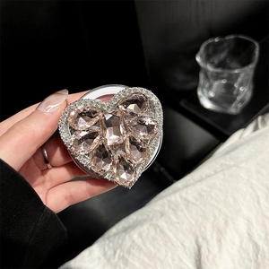 Macro shot of heart-shaped rhinestone phone grip with pink gems and hand-held detail