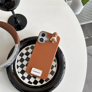 Detailed view of brown lychee leather phone case with cute corgi doll and slogan
