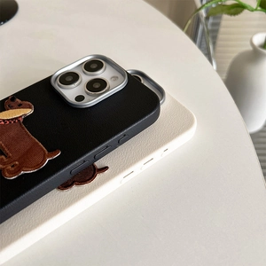 Close-up of leather texture with dachshund embroidery and silver camera ring on phone case