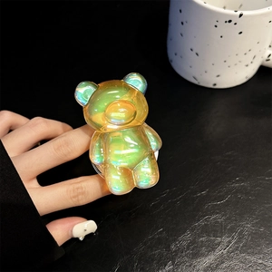 Macro shot of an iridescent bear-shaped phone grip with aurora rainbow finish