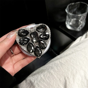 Macro detail of luxury heart-shaped phone grip with black and white rhinestones