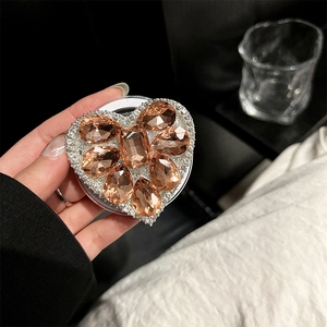 Macro shot of heart-shaped magnetic phone grip with champagne crystals and white gems
