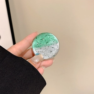 Macro detail of round phone grip with green silver foil flakes in transparent resin
