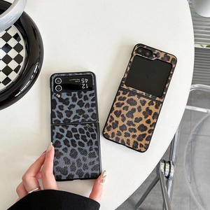 Detail of grey and brown leopard print leather cases for foldable flip phones on a white table