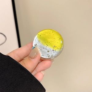 Detail of round yellow phone grip with silver foil accents and transparent finish