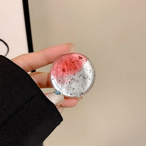 Detail of a transparent phone grip with red and silver foil gradient texture in hand