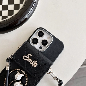 Detail of black leather case with quilted wallet, Smile crystal decor and tulip charm