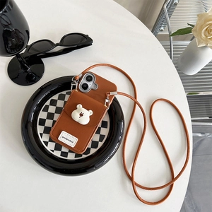 Brown leather iPhone case with bear card holder and crossbody strap on checkered tray