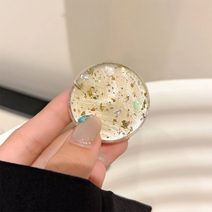 Detail of round resin phone grip featuring aesthetic gold leaf and silver foil flakes