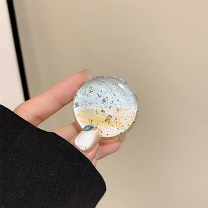 Detailed macro view of a round resin phone grip with blue-yellow gradient and silver foil