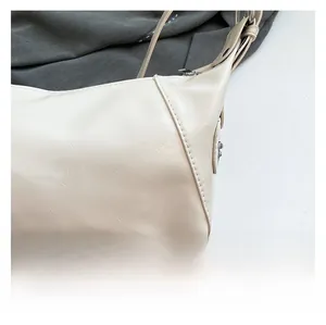 Close-up of cream shoulder bag showing detailed leather texture and fine stitching work