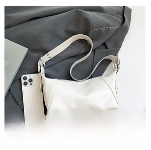 Minimalist beige underarm bag detail showing size comparison with a smartphone