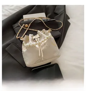 Detailed close-up of embroidery pattern and pearl handle on the white bucket bag