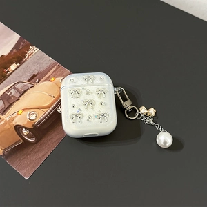 Detail of white glitter AirPods case with silver bows and a pearl charm keychain