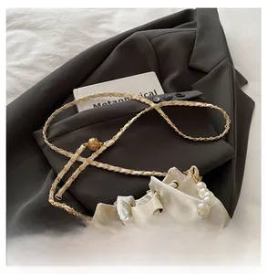 Detail of floral bucket bag with pearl handle and golden chain strap against grey blazer