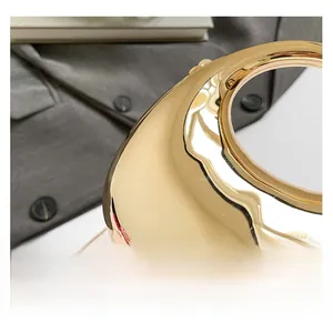 Detailed close-up of golden mirrored evening clutch with ring handle and metal chain