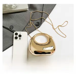 Close-up of golden crescent evening bag with metallic mirror finish and chain strap