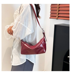 Detail of burgundy glossy shoulder bag showing metallic zipper and adjustable leather strap