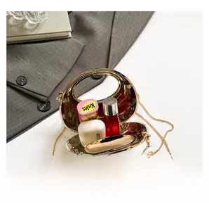Internal storage view of gold-framed acrylic box bag with chain and round handle