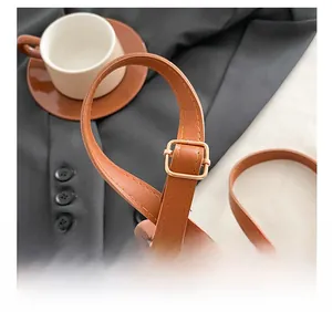 Detail of adjustable brown leather strap with golden buckle and precision stitching