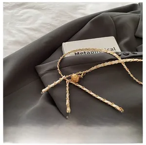 Close-up of woven gold metal chain with pearl bucket bag hardware on grey fabric