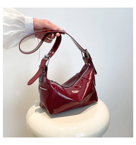 Détail du sac bandoulière en cuir verni bordeaux avec œillets argentés et fermetures