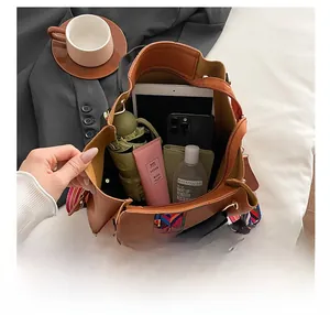 Brown bucket bag showing large capacity with essentials and woven colorful shoulder strap