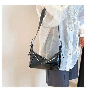 Detail of glossy black patent leather shoulder bag with silver adjustable buckle