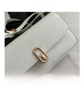 Détails du fermoir rotatif ovale doré sur un sac à main en cuir blanc chic