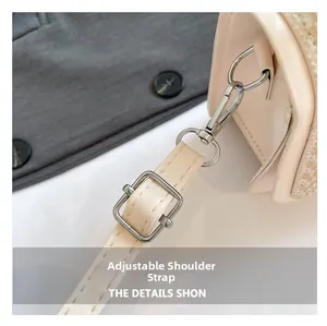 Close-up of adjustable cream leather shoulder strap with silver metal buckle and hooks