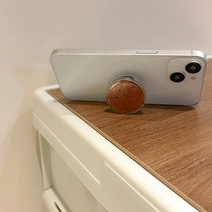 Detail of reddish-brown marble textured phone socket grip on a white smartphone