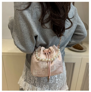 Detail of pink satin bucket bag with floral embroidery and pearl handle accessories