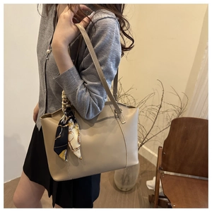 Chic beige tote bag with a decorative floral scarf on model in a cozy interior setting