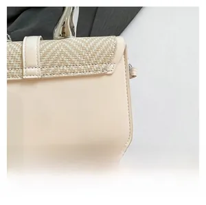 Detail shot of a cream leather handbag with woven straw texture and silver metal handle