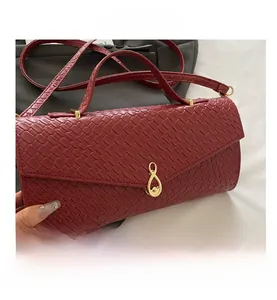 Dettaglio della trama in pelle bordeaux e fibbia dorata a forma di 8 sulla borsa a tracolla