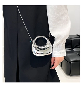 Macro detail of silver mirror hollow moon clutch bag with slender metal chain strap
