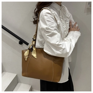 Brown tote bag detail featuring white contrast stitching and a vintage silk scarf handle