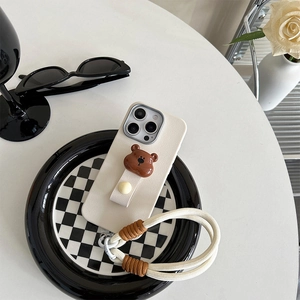 Close-up of beige leather iPhone case with bear charm and thick cotton neck strap