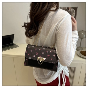 Detail of floral print crossbody bag with gold chain strap and metal lock closure