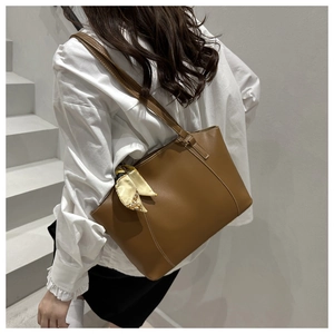Close-up of brown vintage leather tote bag featuring a floral scarf detail on the handle