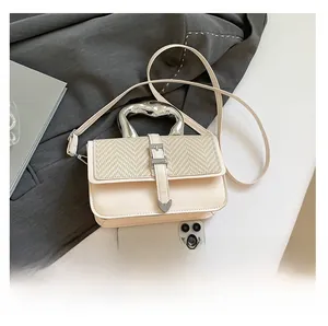 Chic beige woven handbag detail with irregular metal handle and smartphone for scale