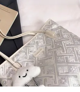 Detail of light gray embroidered tote bag with Creative Cat label and cloud charm