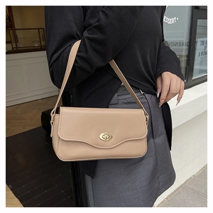 Dettaglio della borsa baguette beige in pelle liscia con chiusura rotante ovale dorata