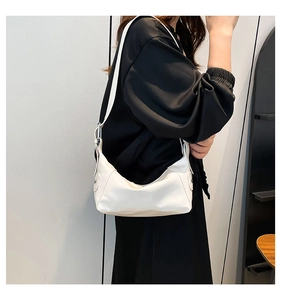 Detailed side view of a white crescent shoulder bag on model showing matte texture