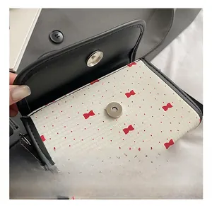 Detailed view of polka dot crossbody bag featuring a round magnetic metal buckle