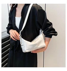 Close-up of white crescent shoulder bag with silver side zippers on black outfit