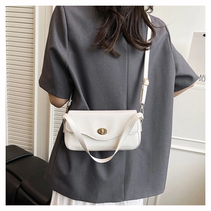 Detail of minimalist cream leather crossbody bag featuring an elegant gold twist lock buckle