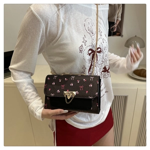 Detailed view of brown crossbody bag with pink floral print and gold chain strap