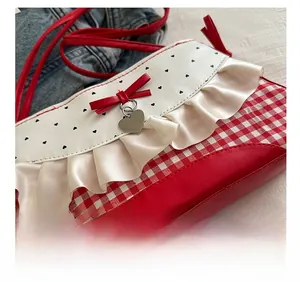 Detail of red checkered fabric with satin ruffles and heart charm on small square bag