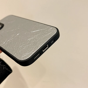 Nahaufnahme der silbernen Knitteroptik-Hülle für iPhone mit präzisen Öffnungen an der Unterseite